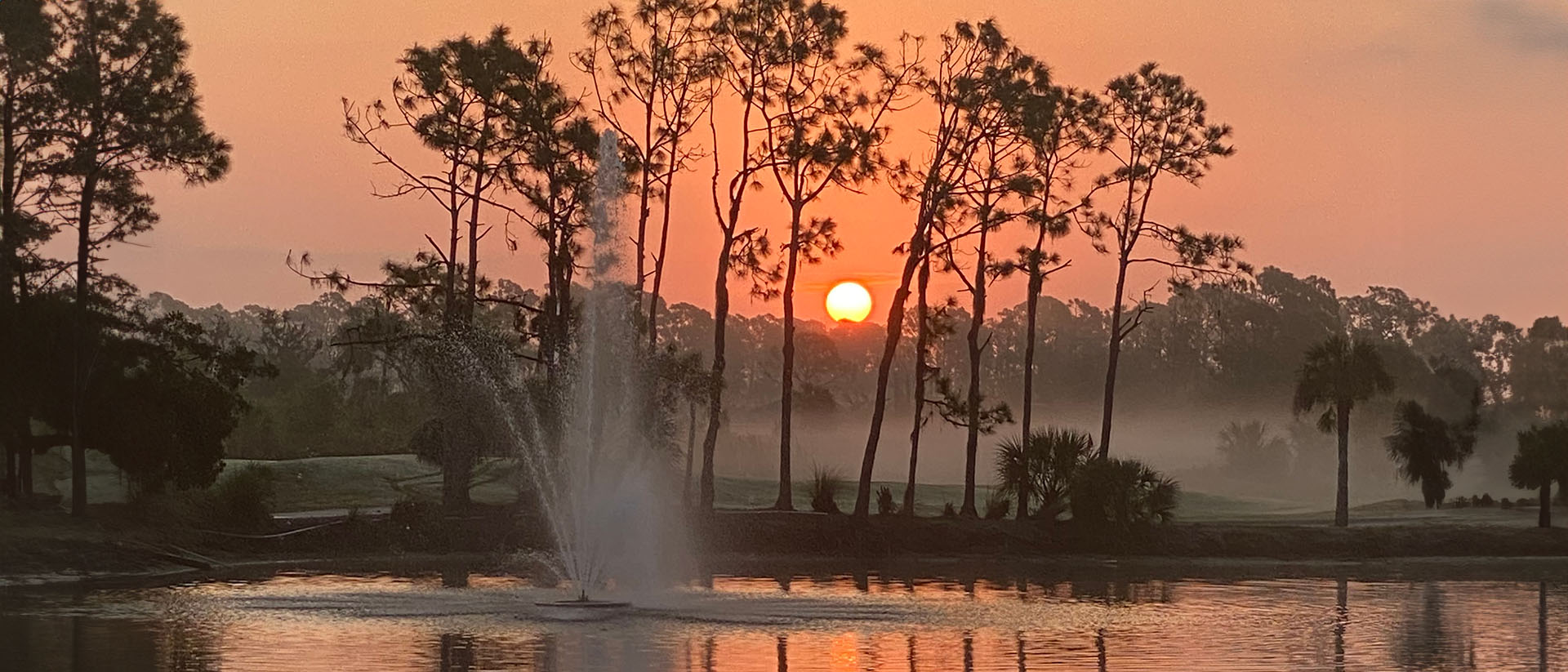 sun sinking behind Slash Pines with fountain in the foreground