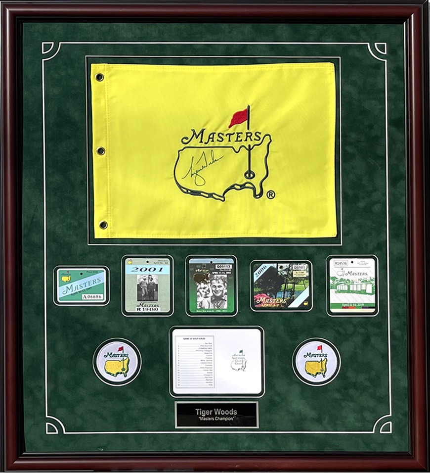 framed display of Masters flag and several patches/badges as well as Tiger Woods nameplate